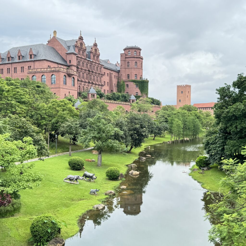 Das an das Heidelberger Schloss erinnernde Gebäude auf dem Huawei Campus in Shenzhen, umgeben von einem künstlichen Fluss und grüner Parkanlage.