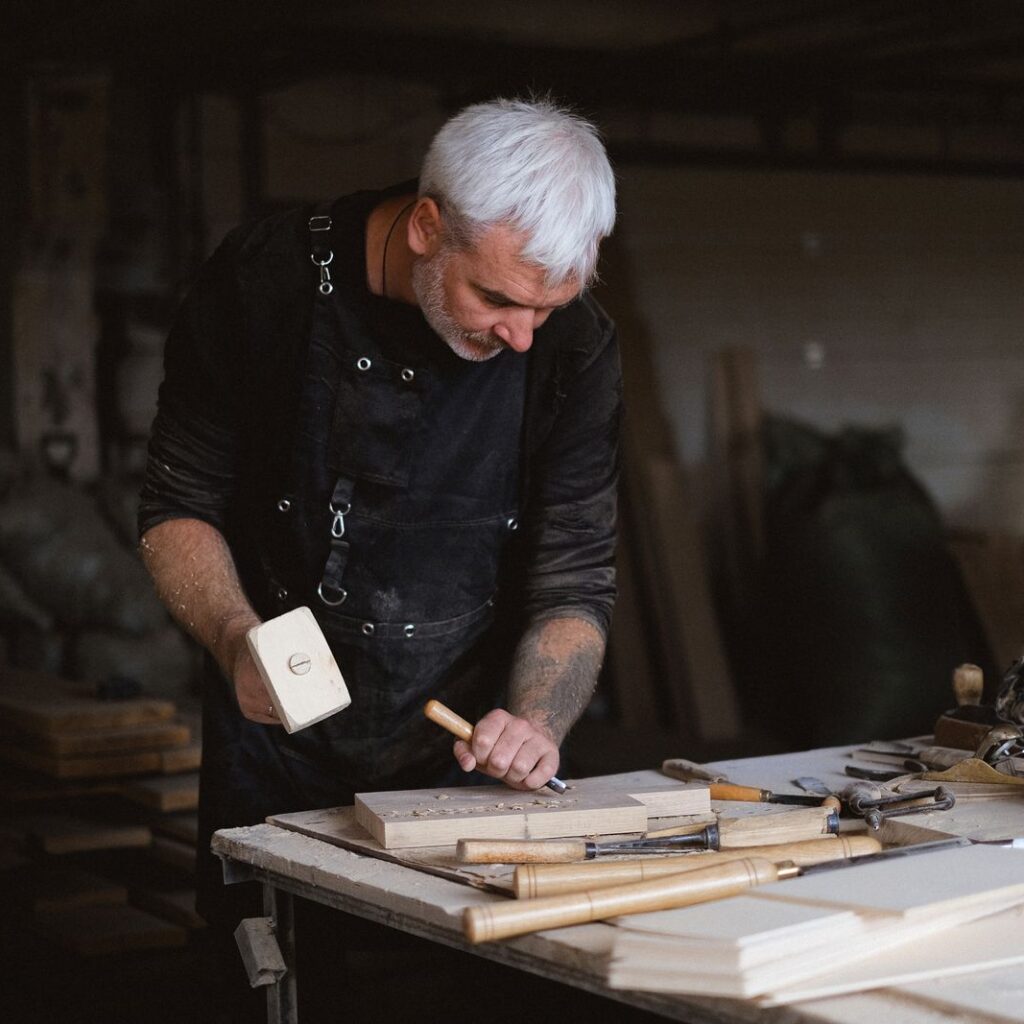 Handwerker bearbeitet ein Werkstück aus Holz in der Werkstatt